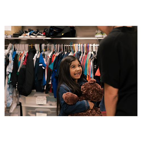 Girl holding a teddy bear in the kids closet