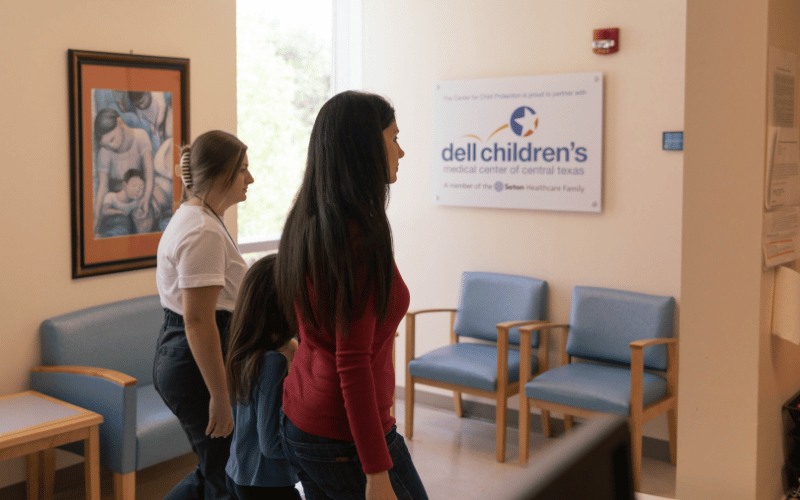 girl walking into medical wing dell childrens with therapist at the center for child protection