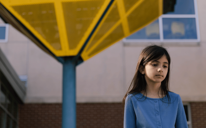 child standing in front of the yellow and blue awnings at the center for child protection