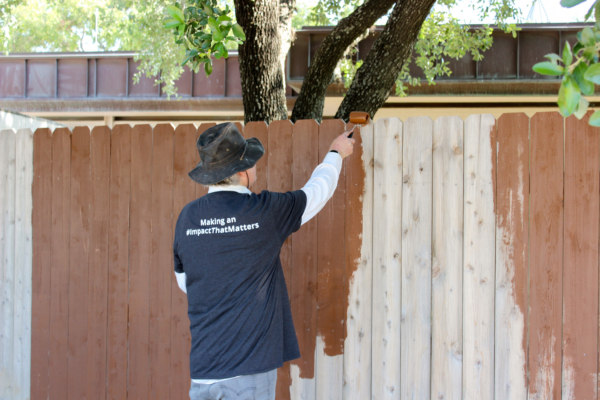volunteer painting the wooden fence